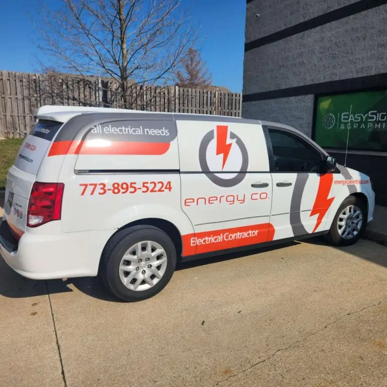 A white van with red and gray graphics for energy co. Electrical Contractor, parked by a building. The van displays a phone number, lightning bolt logo, and all electrical needs text.