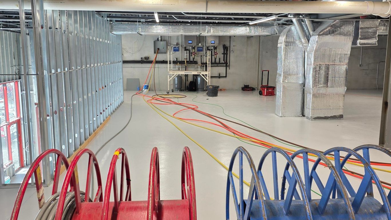 Construction site with spools of wire and exposed ceiling infrastructure.