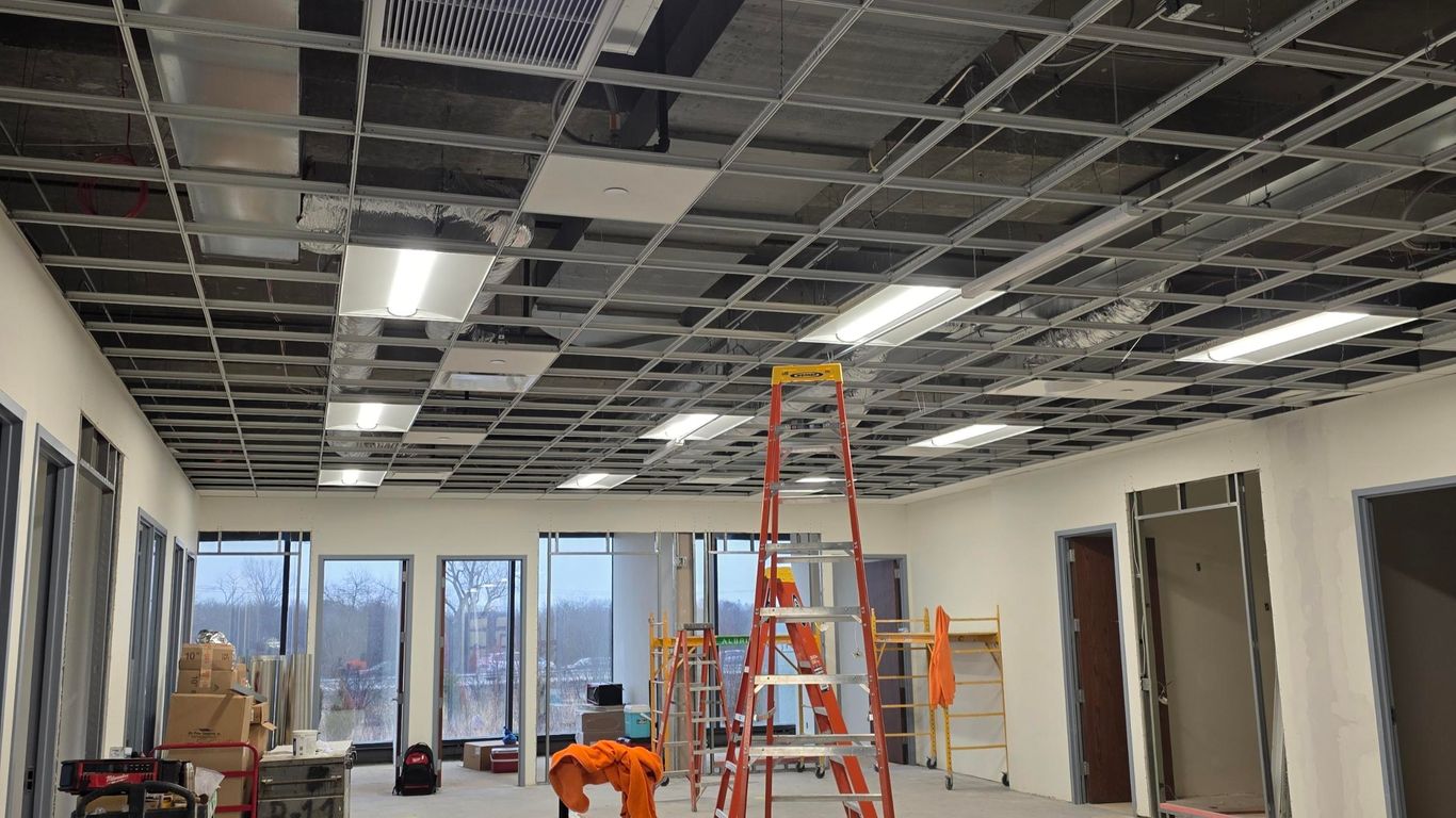 Construction site with ladders, tools, and unfinished ceiling.