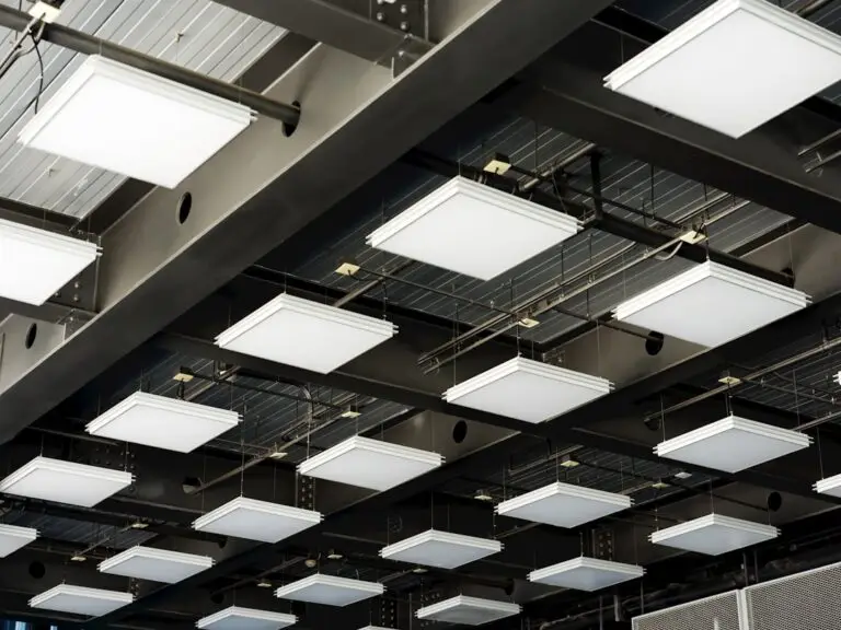 A ceiling with multiple square, white LED panel lights arranged in a grid pattern, suspended from metal beams—an energy-efficient setup that can significantly reduce lighting costs and shorten the LED retrofit payback period.