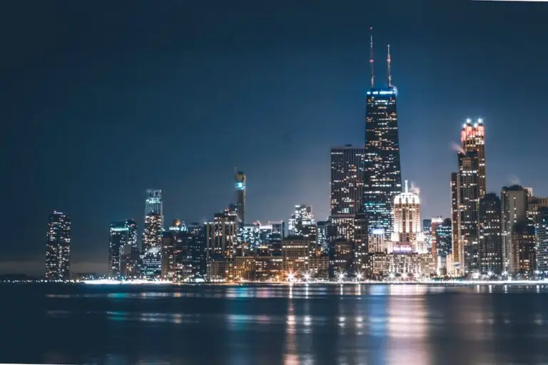 Chicago city skyline at night, with illuminated skyscrapers reflecting on the calm surface of Lake Michigan under a dark, clear sky—a vibrant scene that highlights the vital role of Chicagoland emergency electrical repair in keeping the city’s lights shining bright.