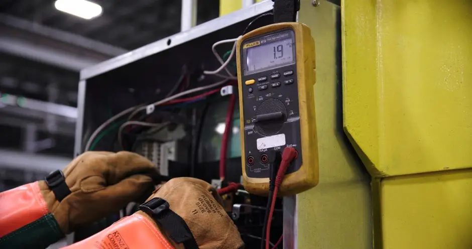 technician using digital multimeter on generator control panel